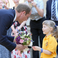 2歳になるイザベラ・ローリングスちゃんから花束を受け取る英ウィリアム王子
