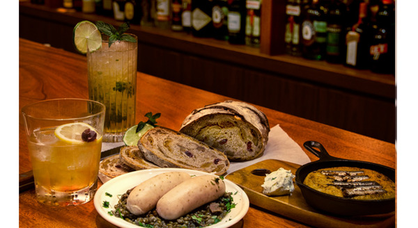 「自由が丘ベイクショップ」監修のフードメニュー右から：「オイルサーディンとジャガイモのガレット」（900円）、「ミュンヘン ヴァイスブルスト」（1,000円）、「イチジクとクルミのカンパーニュ」（500円）、「ディス アメリカン ライフ」（1,200円）、「スパイシーモヒート」（1,200円）